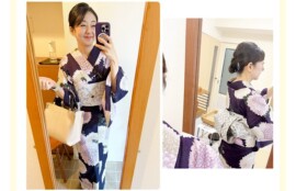 鏡越しに撮影した、紫の菊模様の浴衣に淡い帯を合わせた正面姿。ベージュのバッグを持ち笑顔。