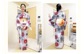 白地に黒と赤の大輪柄の浴衣を着て、オレンジの帯を結んだ笑顔の生徒さん。