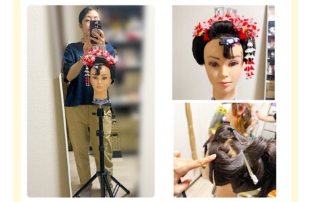 新日本髪の土台作りをしている様子（ウィッグを使った研修風景） まとめ髪を上に引き上げ、形を整えている場面 鏡越しに研修の様子を撮影する講師とウィッグ